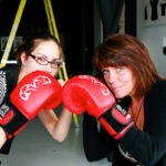 Comment transformer des employés d'entreprise en "véritables" champions olympiques ? 15 Coulisses du calendrier Emballages Carrousel : deux employées posent avec des gants de boxe rouges